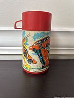 Side view showing General Lee car and action scene graphics on the plastic thermos.