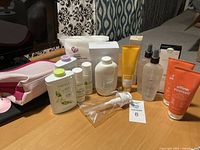 Full view of all toiletries arranged on surface, featuring branded bottles, tubes, pack of cosmetic pads, and cosmetic bag