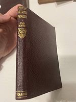 Front cover and spine of "The Pilgrim's Progress" showing dark brown textured leather-like material with gold embossed title and author name by Collins.
