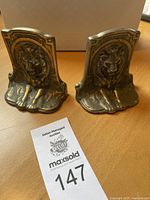 Pair of bronze lion bookends side by side showing size and patina differences