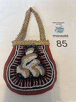 Full front view of antique Haudenosaunee (Iroquois) beaded pouch with intricate beadwork on maroon fabric and beaded handle.