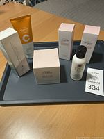 View of all five unopened skincare products on tray, showing various Isa Knox Anew Clinical and Avon Anew boxes and tubes.