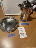 Photo of the lot showing the Birks Regency Plate silverplate coffee pot and the Derby Silver Co quadruple plate tray on a wood table surface with price and size indications.