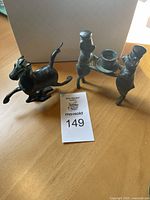 Photo of the two bronze sculptures displayed together, showing the chef pig candleholder and the flying horse statue