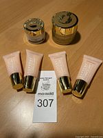 Lot of 6 Elizabeth Grant skincare products with 4 pink tubes and 2 jars on wood surface.