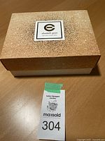 Closed gold glitter textured box with Elizabeth Grant logo and tagline "GET INTO YOUR SKIN".