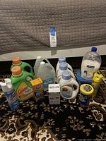 Full view of all cleaning and laundry products arranged together on carpet with the lot tag in background.