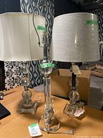 Three lead crystal table lamps shown on table with two having shades, one missing a shade. Metal fittings and different finials noted.