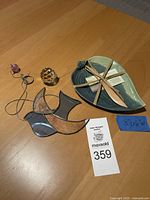 Full view of the lot items arranged on wooden table: pottery leaf plate, stained glass bird, metal bird, crystal balls.