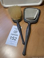 Photo showing the hair brush and hand mirror side by side on a wooden surface.