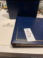 Closed blue binder titled 'The Story of Canada' with Excelsior Collectors Guild folder and lot tag.