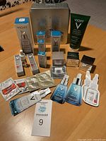 Overview photo showing all 11 products including two boxes of Liftactiv Supreme H.A. Serum, a green tube of Normaderm cleanser, several small boxes, sachet samples, and a metal Vichy tin.