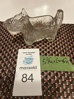 Clear glass creamer shaped like a Scottie dog, showing front and right side with note of size and auction tag.