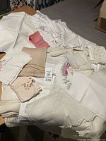 Multiple vintage linens arranged including embroidered table runner, napkins, and handkerchiefs showing variety of textures and details.