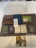 Photo showing all various playing card decks and collectible cards arranged on table next to clear plastic container