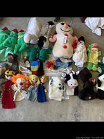 Overview of the vintage puppets showing multiple animal and character puppets including green frogs, snowmen, cows, and several human figures.
