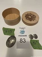 Photo of oval brooch, clip-on earrings, round wooden box with lid removed and placed next to box, measurement tags for brooch and earrings shown
