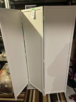 Photo of the white wooden folding divider showing three rectangular panels connected with hinges, standing upright.