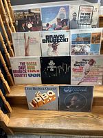Eleven LP album covers and vinyls by The Dave Brubeck Quartet arranged on steps showing condition and titles.