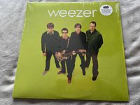 Front cover of 2016 Weezer vinyl album with band photo and lime green background, shrink wrapped with sticker.