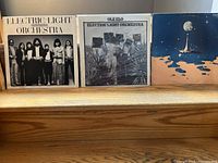 Three Electric Light Orchestra vinyl record albums displayed side-by-side on a wooden step: 'On the Third Day,' 'Ole ELO,' and 'Time'.
