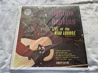 Front cover of Lightnin' Hopkins 'Live at the Bird Lounge' vinyl album shrink wrapped showing vintage image of Lightnin' Hopkins playing guitar.