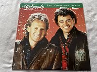 Front cover of Air Supply The Christmas Album showing the band members with a sticker remnant on the cover.