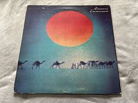 Front cover of Santana's Caravanserai album showing a red sun with camels and figures in a desert scene.
