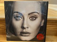 Front cover of Adele 25 album showing close-up portrait of Adele's face with shrink wrap.
