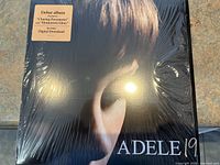 Front cover of Adele's '19' vinyl LP album wrapped in original shrink wrap, showing partial image of Adele's face and album title.