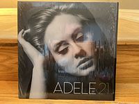 Front cover of Adele's 21 album showing black-and-white portrait of Adele in thoughtful pose.