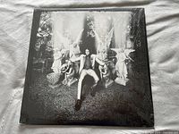 Front cover of the Jack White Lazaretto vinyl record showing black and white photo with Jack White sitting surrounded by statues.