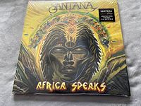 Front cover of Santana Africa Speaks album with vibrant African-inspired art, sealed in shrink wrap showing keystone text for the title and band.