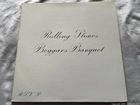 Front of vinyl album cover showing white background with cursive Rolling Stones Beggars Banquet title text.