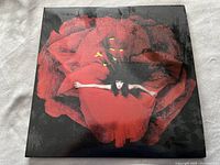 Front cover of The Smashing Pumpkins "Adore" album showing a person in red dress against a large red flower on a dark background.