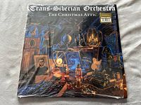 Front view of the shrink-wrapped album cover showing detailed Christmas attic setting with various vintage toys, instruments and decorations.