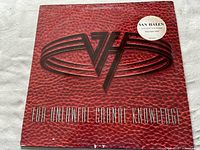 Front of album cover with red textured pattern and embossed VH logo, round promotional sticker