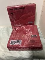 Two packs of IKEA Fantastisk red paper napkins, unopened in plastic packaging, showing brand and quantity.