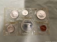 Front side of 6 coins sealed in clear plastic packaging with commemorative images.