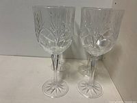 Four clear crystal wine glasses displayed against a white background showing cut leaf/starburst pattern on bowls and star pattern on base.