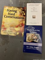 Three work-related books stacked and displayed to show front covers: 'Having Hard Conversations', 'The No Asshole Rule', and 'The Magic-Weaving Business'.
