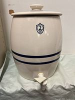 Front view of dispenser showing spigot, stripes, and shield emblem