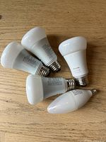 Five Philips Hue smart bulbs on a wooden surface, showing overall contents of the lot.