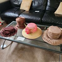 Four women's hats on a glass coffee table showing full set.