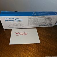 Box of LED Digital Loud Alarm Clock with Bed Shaker, model CR1001EM, shown from side and angle views.