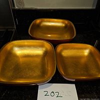 Set of three square bowls with red exterior and gold interior, varying sizes.