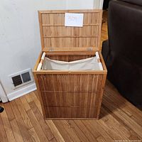 Front and inside view of the bamboo hamper with lid open showing fabric liner inside.