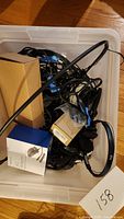 Photo showing bin filled with tangled cords, boxes, and headphones, highlighting items included in the lot.