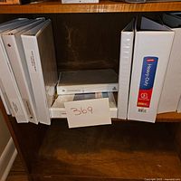 Shelf with seven white binders including labeled heavy-duty and volume binders.