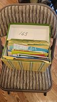 Green and yellow striped storage box containing organized blank occasion cards with tabbed dividers.
